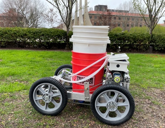 Original outdoor photograph of the Camel Bots team prototype, with four wheels, an aluminum frame, stacked treatment buckets and electronics